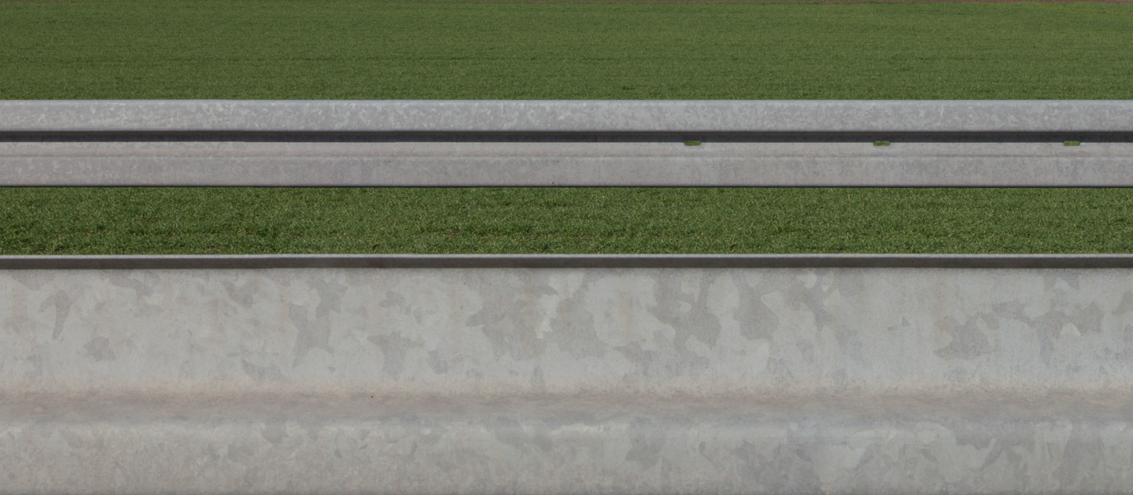 minimalistic horizontal image, showing two guardrails against grass – letting them seem two-dimensional