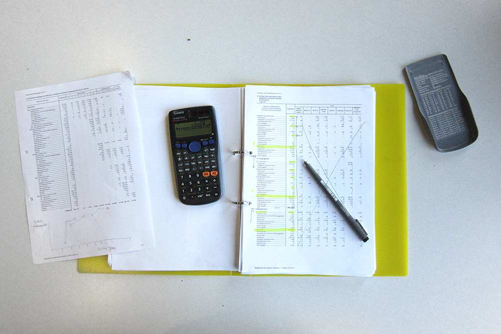 desktop with a folder of tables, a calculator and a pen