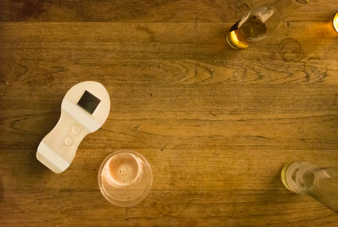 the motion karaoke prototype lying on a bar table between bottles and glasses